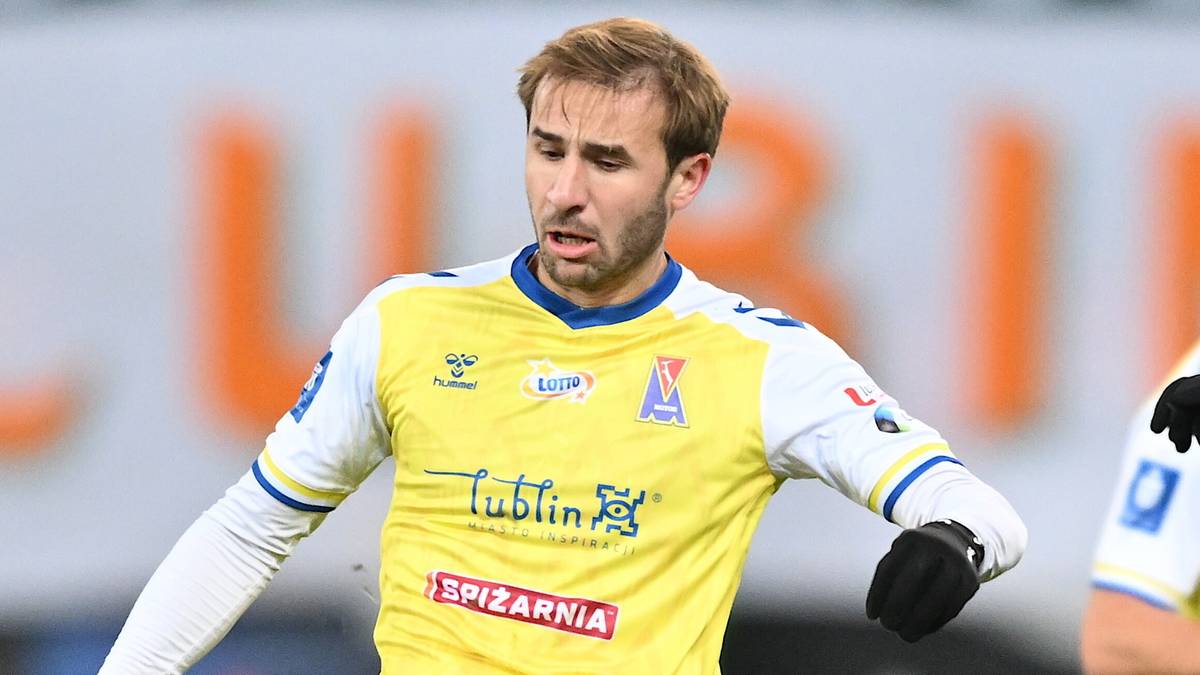 Piłkarz w ż&oacute;łto-białej koszulce z logo "Lublin" i "Epizarnia", patrzący w bok z lekko otwartymi ustami.