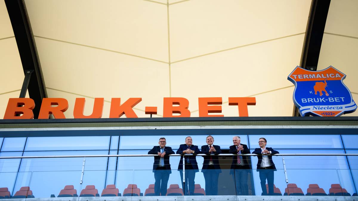 Napis "BRUK-BET" nad szklaną fasadą, obok herb klubu Termalica Bruk-Bet z Niecieczy.
