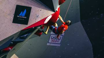 Sportowiec wspina się po ścianie wspinaczkowej, trzymając się uchwytu.