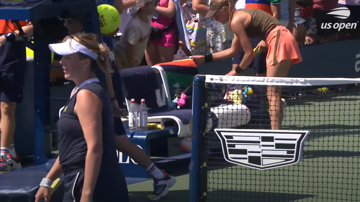 Dwie zawodniczki na korcie tenisowym US Open, jedna z nich odwraca się od siatki i oddala, druga stoi przy siatce z piłkami.