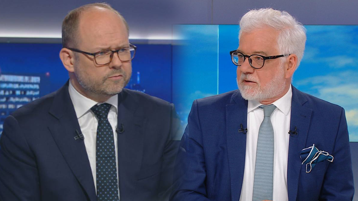 Dw&oacute;ch mężczyzn w garniturach podczas dyskusji, jeden z nich ma okulary.