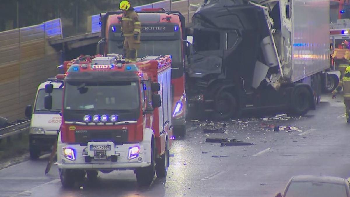 Zniszczone ciężar&oacute;wki i wozy strażackie na autostradzie po wypadku drogowym.
