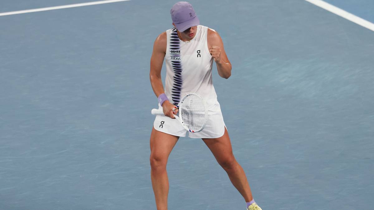 Tenisistka Iga Świątek na korcie, w białej sukience i fioletowej czapce, świętująca zwycięstwo.