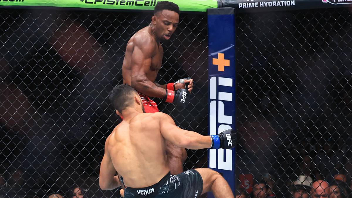 Dwóch zawodników MMA w klatce UFC. Jeden zawodnik wykonuje wysokie kopnięcie, podczas gdy drugi próbuje się obronić.