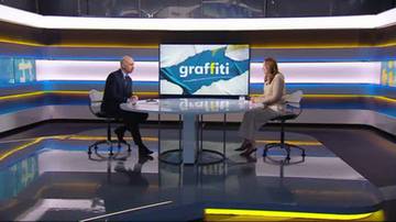 Dwoje ludzi rozmawia w studiu telewizyjnym. Na ekranie w tle widnieje napis "graffiti".
