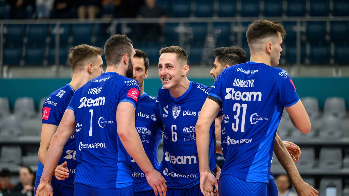 Grupa siatkarzy w niebieskich koszulkach z napisem "Steam" i numerami, stojący blisko siebie i rozmawiający ze sobą.