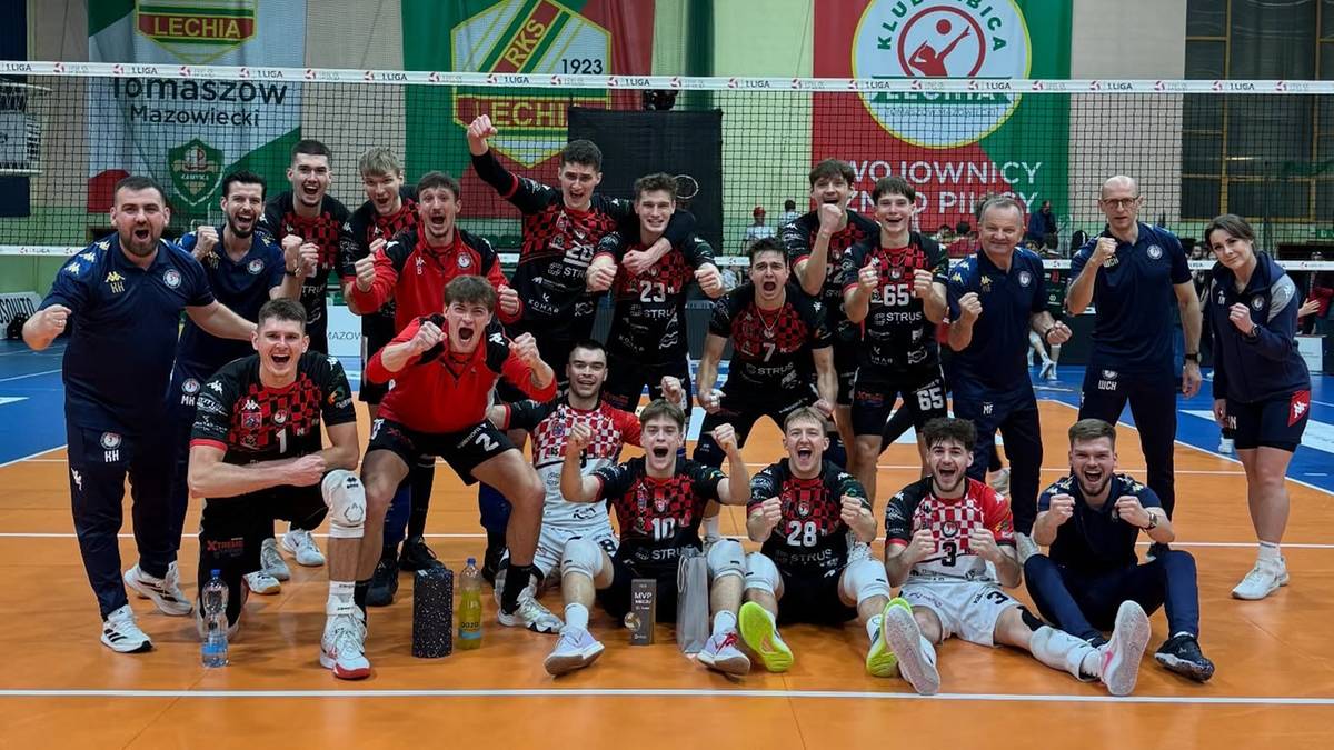 Drużyna siatkarska pozuje do wspólnego zdjęcia na boisku.