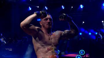 Marcin Łazarz unosi ręce w geście zwycięstwa na ringu.