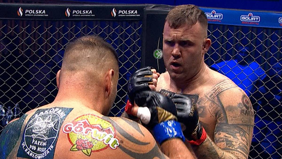 Dwóch zawodników MMA w klatce podczas walki.