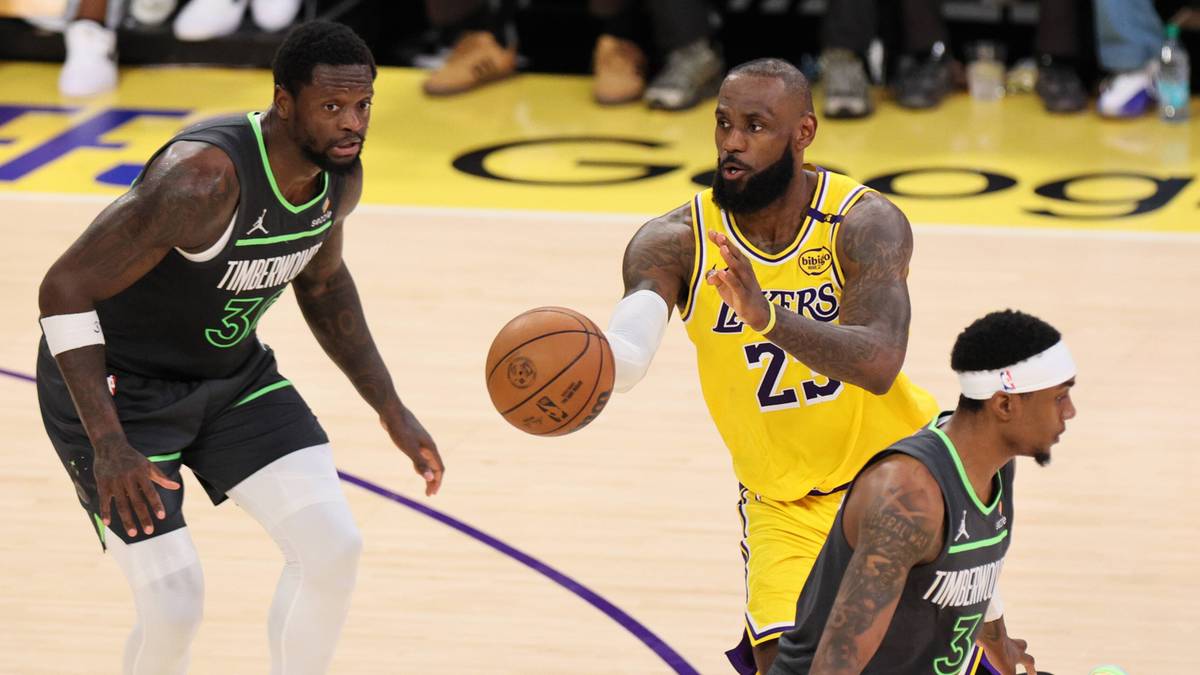 Trzech koszykarzy podczas meczu, jeden z nich podaje piłkę.