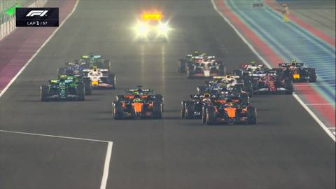 Grupa samochodów Formuły 1 rozpoczyna wyścig na torze w Katarze, z pojazdem bezpieczeństwa przed nimi.