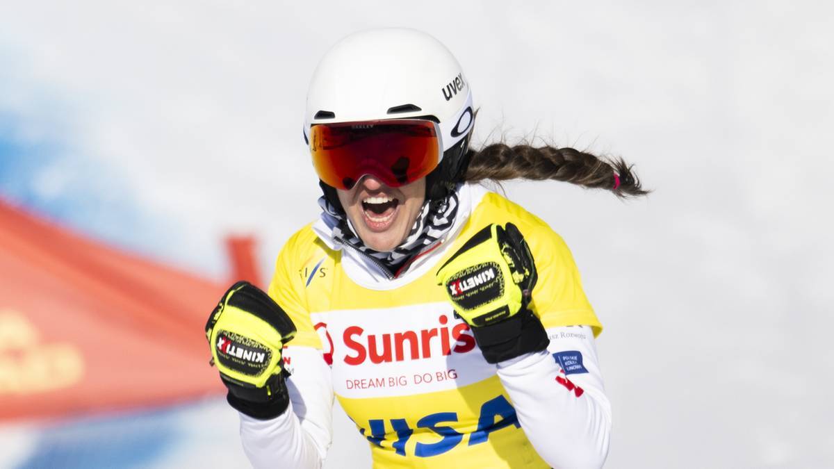 Zawodniczka narciarstwa alpejskiego w kasku i goglach cieszy się ze zwycięstwa, zaciskając pięści.