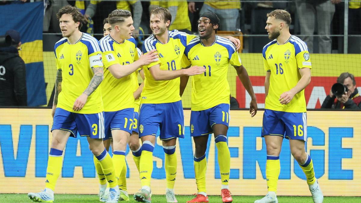 Piłkarze w ż&oacute;łtych strojach piłkarskich świętują na boisku, na drugim planie widać kibic&oacute;w na trybunach.