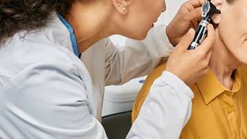 Lekarz bada ucho pacjenta otoskopem.