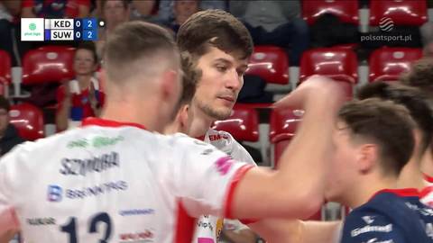 Siatkarze ZAKSY Kędzierzyn-Koźle w akcji podczas meczu z MKS Ślepsk Malow Suwałki. Dwóch zawodników w białych koszulkach z numerem 12 i nazwiskiem "Szymura" jest w centrum uwagi, jeden z nich wykonuje atak, podczas gdy drugi obserwuje grę.