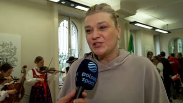 Małgorzata Glinka-Mogentale z mikrofonem Polsat Sport w ręku, w tle muzycy grający na skrzypcach i wiolonczeli.