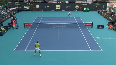 Dw&oacute;ch tenisist&oacute;w na niebieskim korcie tenisowym z siatką pośrodku. Jeden gracz stoi przy siatce, drugi przy linii końcowej.