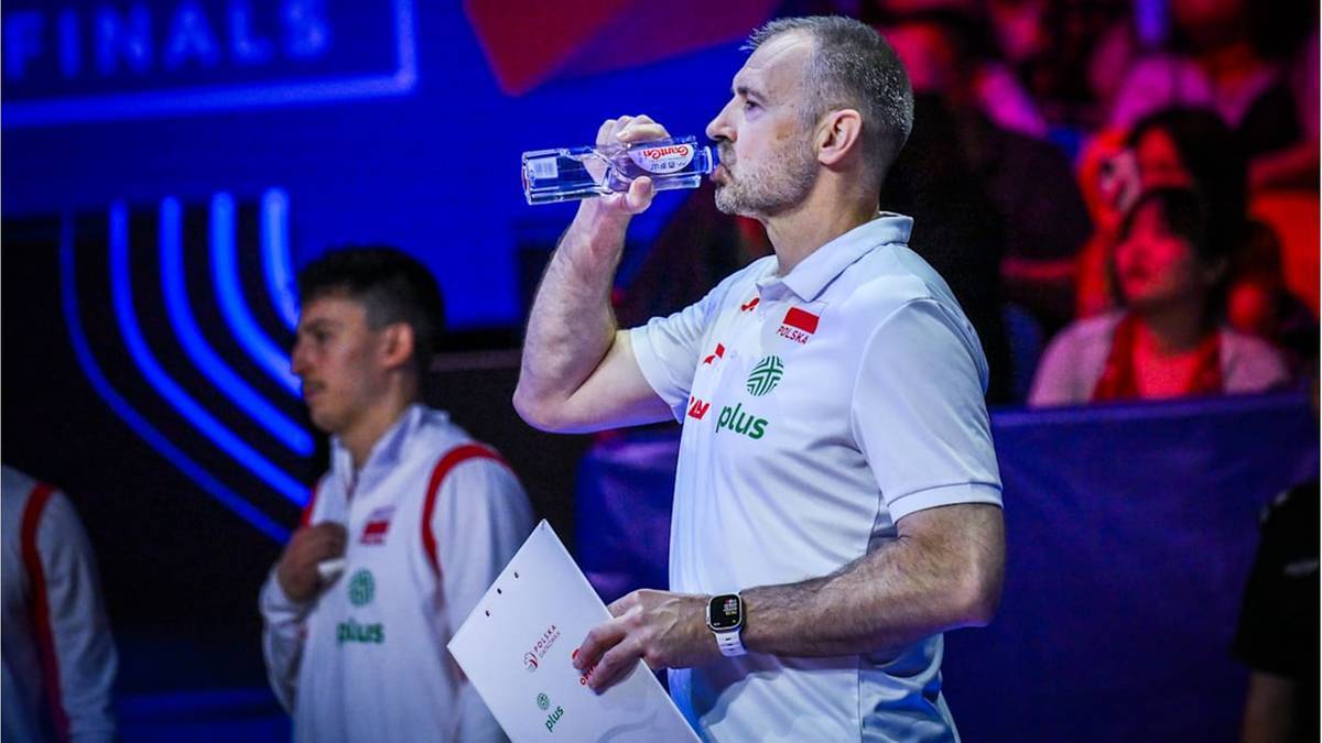 Trener męskiej drużyny koszyk&oacute;wki pije wodę podczas przerwy w meczu.
