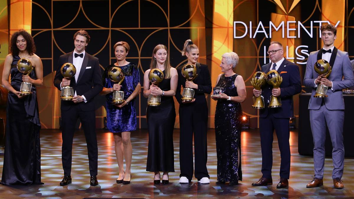 Grupa osób na scenie odbierająca nagrody, większość trzyma trofea.