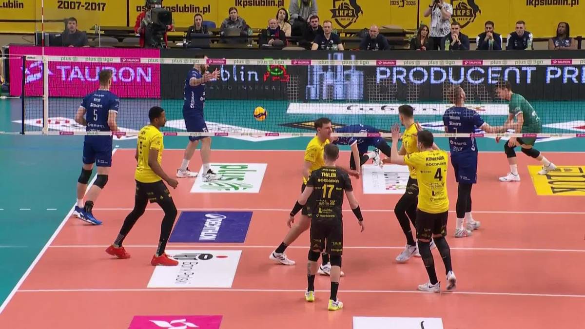 Siatkarze w trakcie meczu PlusLigi, jeden z zawodnik&oacute;w w ż&oacute;łtej koszulce wykonuje zagrywkę.