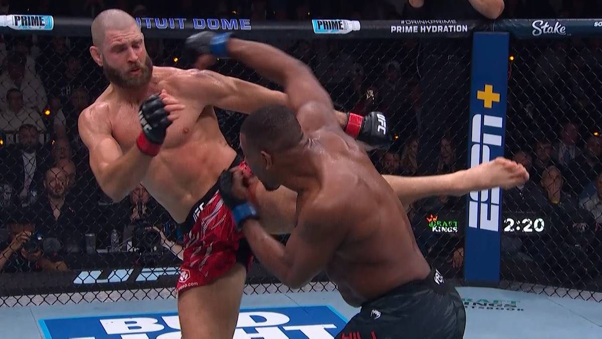 Dwóch zawodników MMA walczy w klatce. Jeden zawodnik wykonuje wysokie kopnięcie.