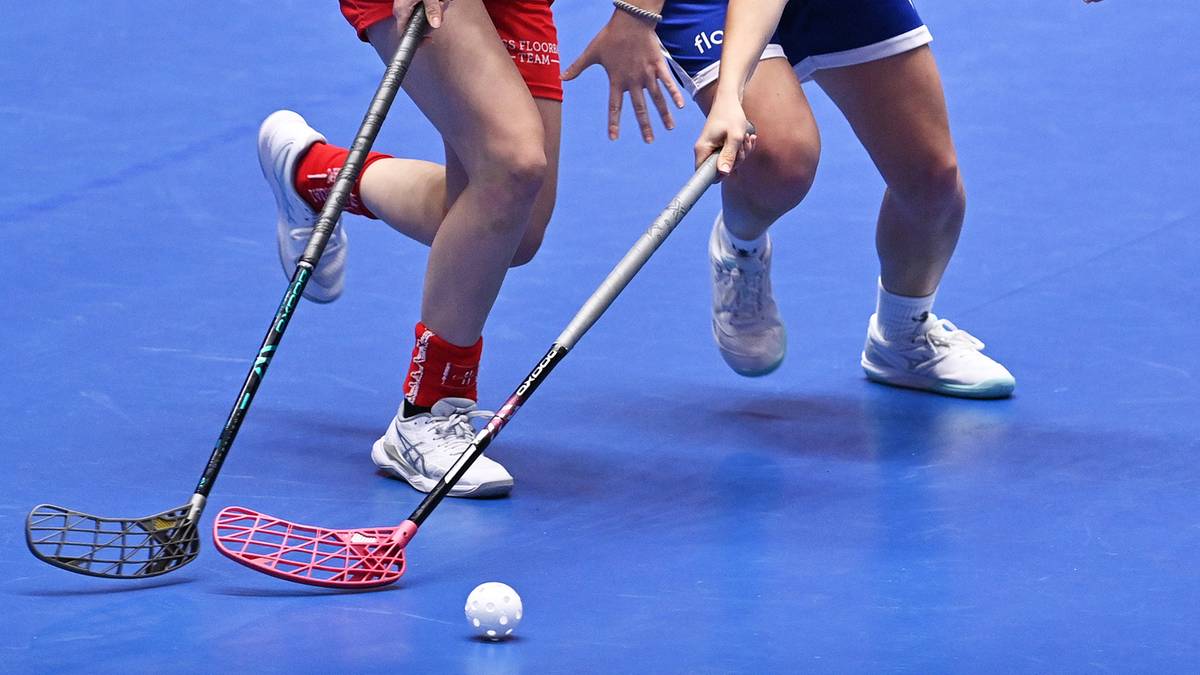 Dwie zawodniczki unihokeja walczące o piłkę na boisku.