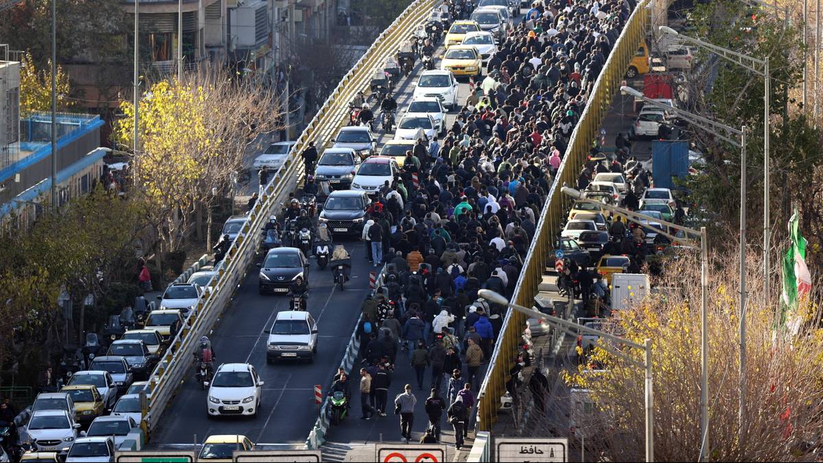 Tłum ludzi idących po moście nad ruchliwą ulicą z samochodami.