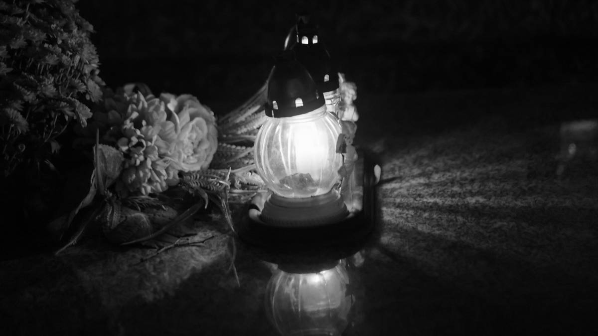 Znicz i bukiet kwiatów na ciemnym tle.