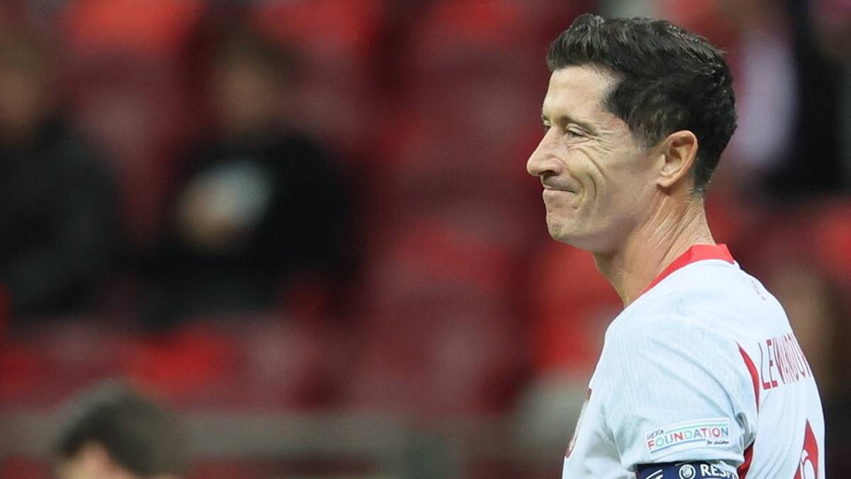 Robert Lewandowski w białej koszulce reprezentacji z opaską kapitańską.