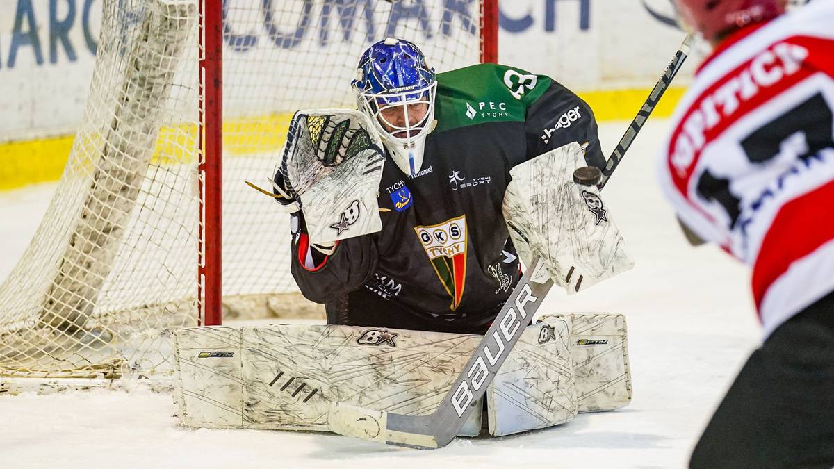 Bramkarz drużyny hokejowej w masce ochronnej i sprzęcie bramkarskim, broniący bramki.