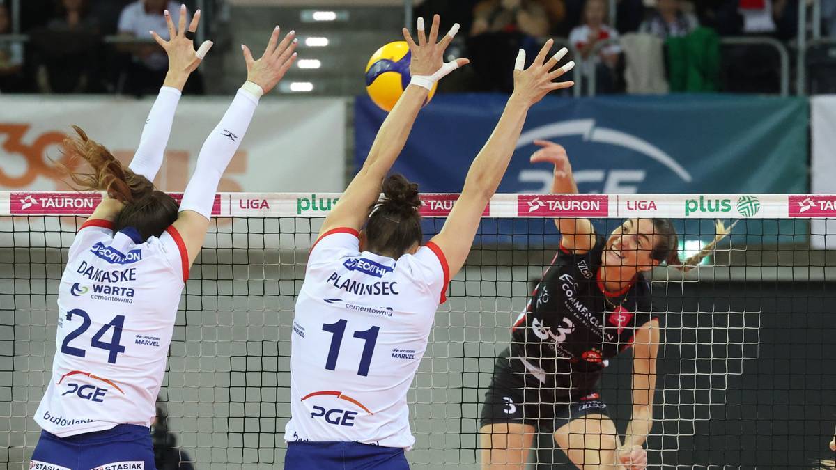 Siatkarki walczą o piłkę nad siatką podczas meczu.
