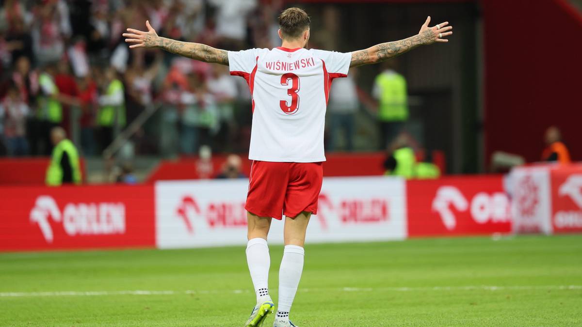 Piłkarz w białej koszulce z numerem 3 i czerwonych spodenkach świętuje na boisku.
