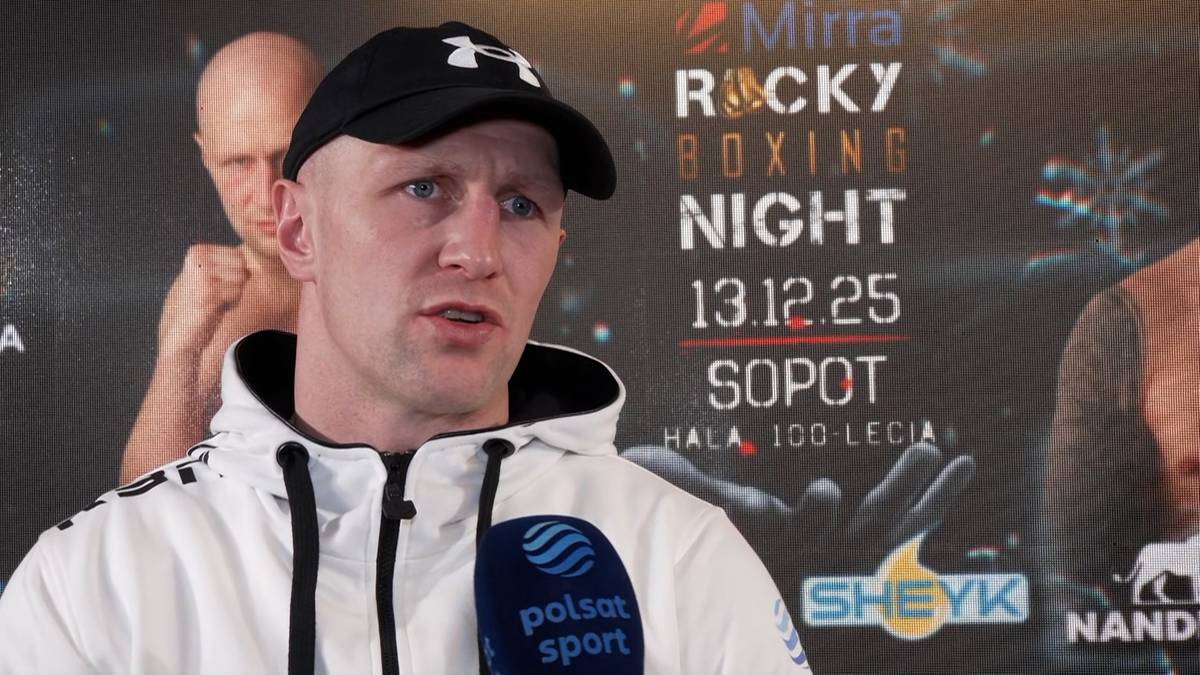 Pięściarz Nikodem Jeżewski w czapce z daszkiem i bluzie z kapturem odpowiada na pytanie dziennikarza.