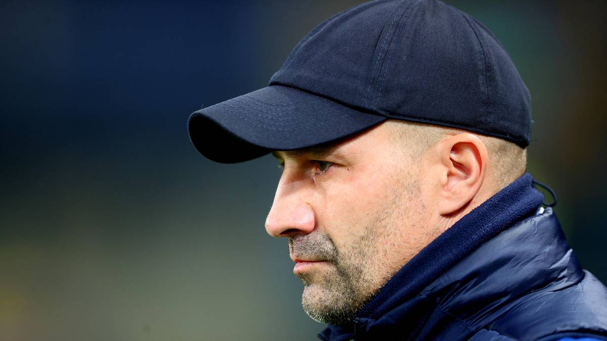 Portret mężczyzny w ciemnej czapce z daszkiem, w pozycji profilowej, patrzącego w bok.