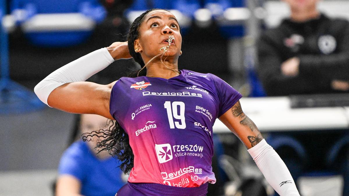 Siatkarka w fioletowej koszulce z numerem 19, wykonuje zagrywkę.