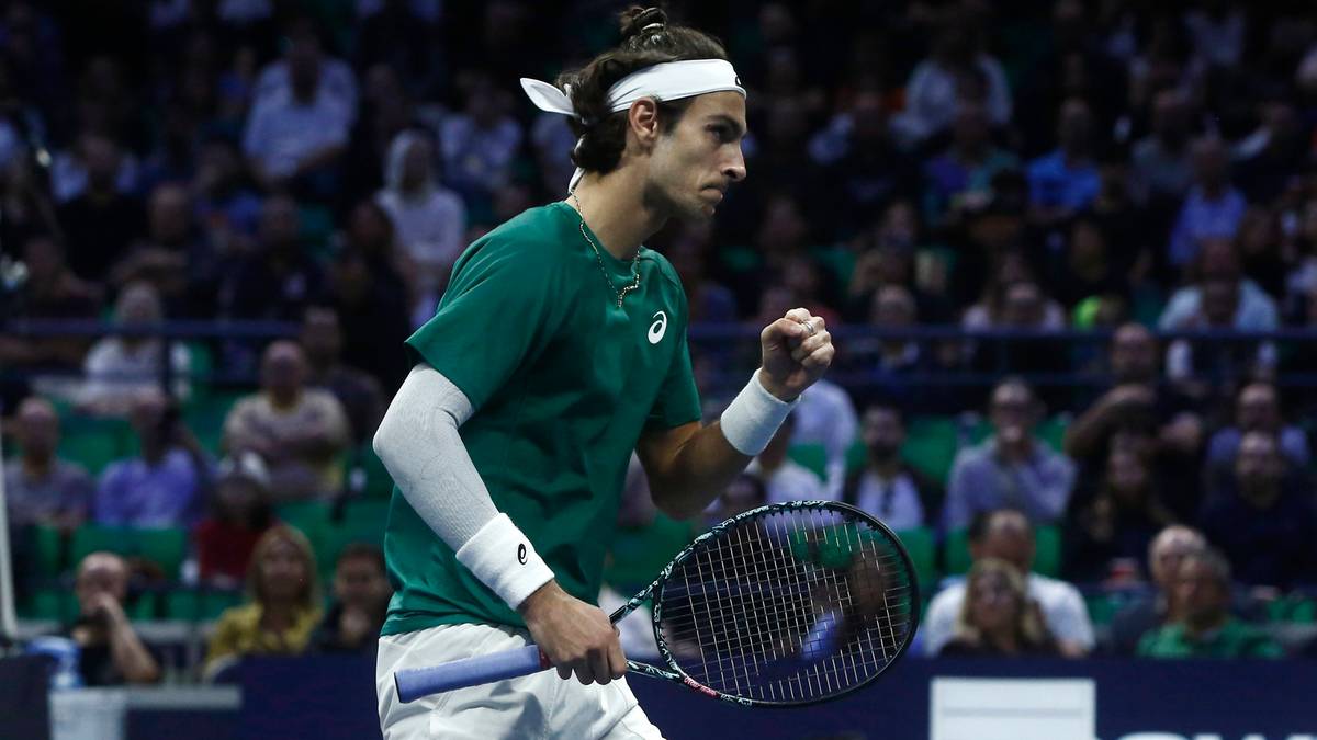 Lorenzo Musetti, tenisista, podczas meczu świętuje punkt, trzymając rakietę i unosząc pięść