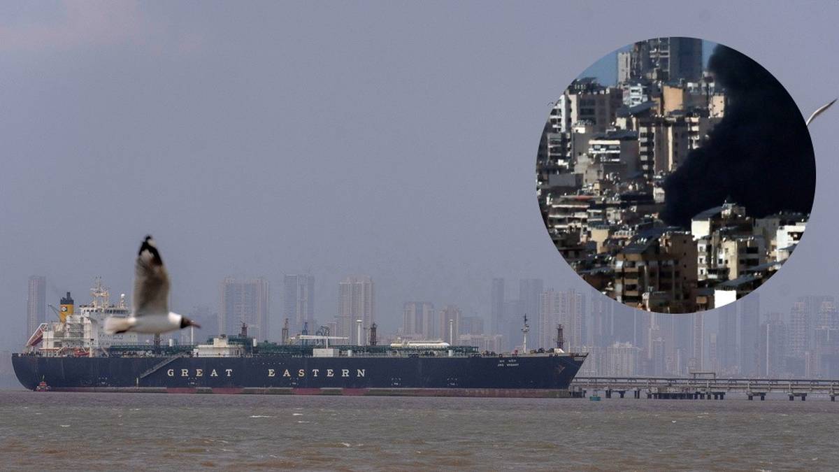 Widok statku towarowego na wodzie z panoramą miasta w tle. W prawym g&oacute;rnym rogu znajduje się okrągłe zdjęcie przedstawiające dym unoszący się nad zabudowaniami.