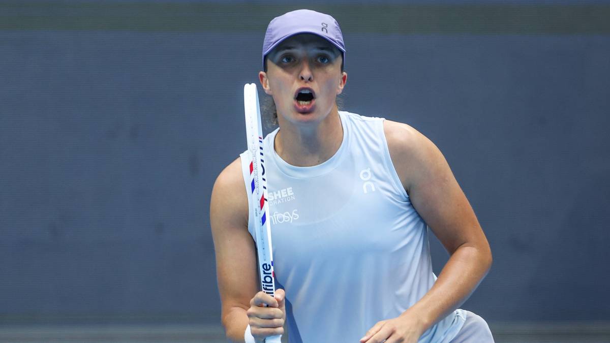 Iga Świątek podczas meczu tenisowego, w akcji z rakietą, z piłką w powietrzu.