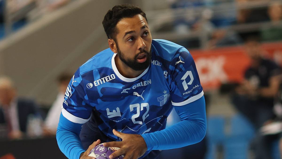 Piłkarz ręczny w niebieskiej koszulce z numerem 22 na piersi trzyma piłkę.