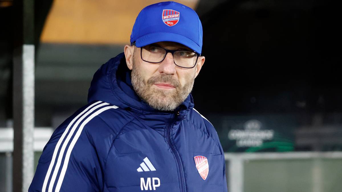 Mężczyzna w okularach i czapce z daszkiem z logo klubu sportowego, ubrany w kurtkę.