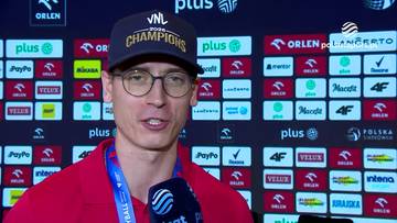 Kamil Semeniuk w czapce z daszkiem "VNL Champions 2023" udziela wywiadu na tle ścianki sponsorskiej.