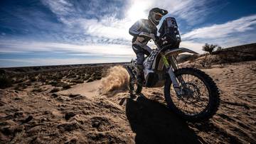 Motocyklista ścigający się po pustynnym terenie.