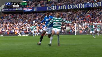 Dw&oacute;ch piłkarzy walczy o piłkę na boisku podczas meczu Rangers FC - Celtic FC. Jeden z nich w niebieskim stroju, drugi w zielono-białym.