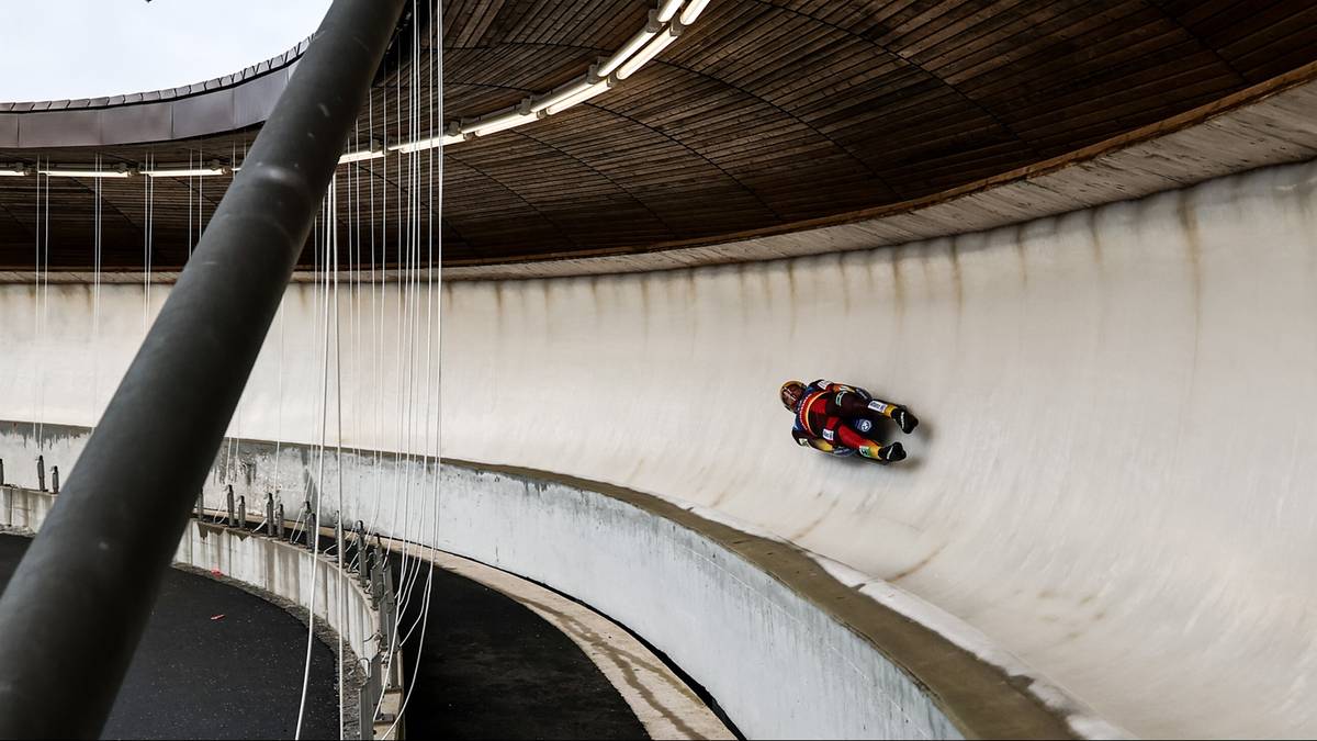 Saneczkarz zjazdowy na zakrzywionym torze lodowym podczas zawod&oacute;w.