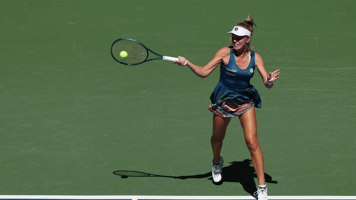 Magdalena Fręch, tenisistka, uderza piłkę rakietą podczas meczu na zielonym korcie tenisowym.