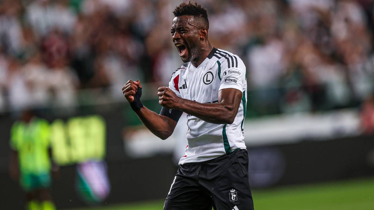 Piłkarz Legii Warszawa w białej koszulce z czarnymi elementami świętuje zdobycie bramki z zaciśniętymi pięściami i otwartymi ustami.