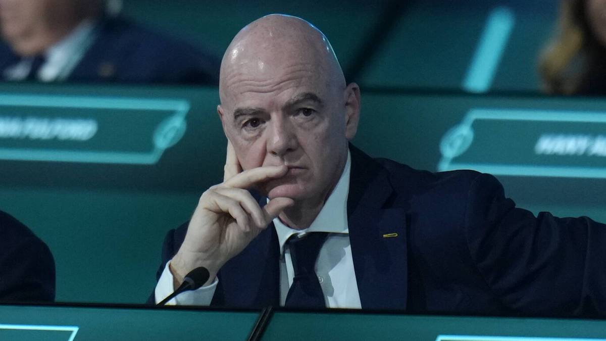 Prezydent FIFA Gianni Infantino siedzi z ręką na brodzie, patrząc przed siebie.