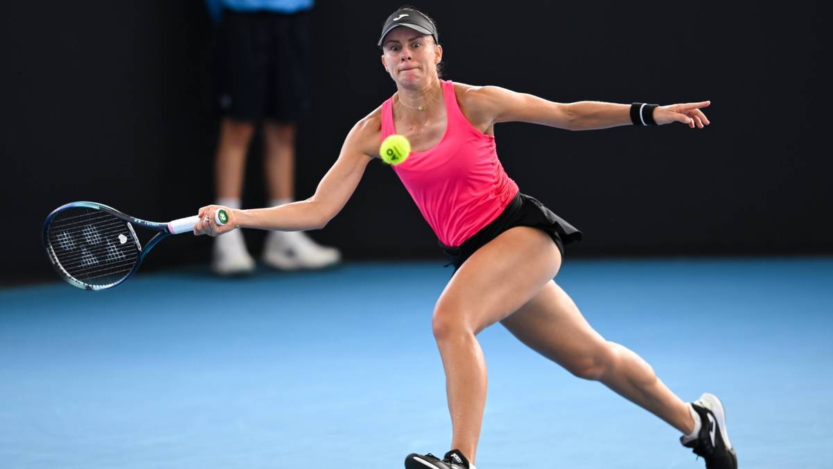 Tenisistka w różowej koszulce i czarnej spódniczce uderza piłkę rakietą podczas meczu.