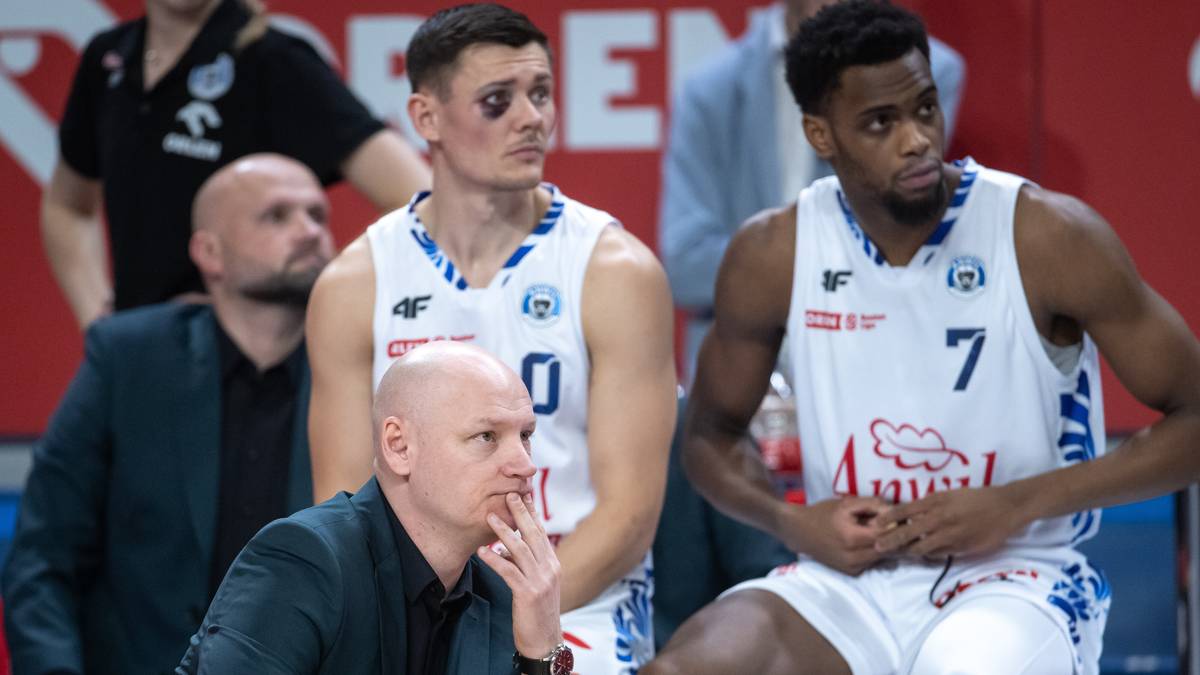 Dwóch zawodników Anwilu Włocławek siedzi na ławce rezerwowych podczas meczu FIBA Europe Cup, jeden z nich ma otarcie pod okiem.