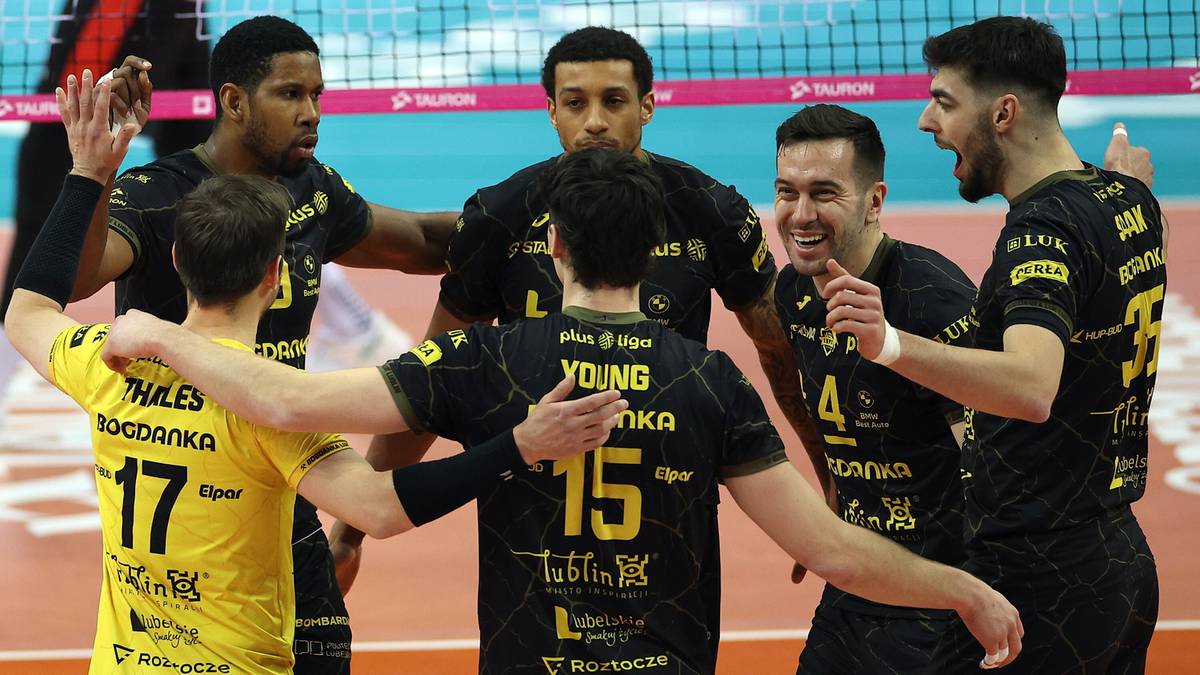 Grupa siatkarzy w czarnych strojach celebrująca na boisku, jeden z nich ma na koszulce numer 15.